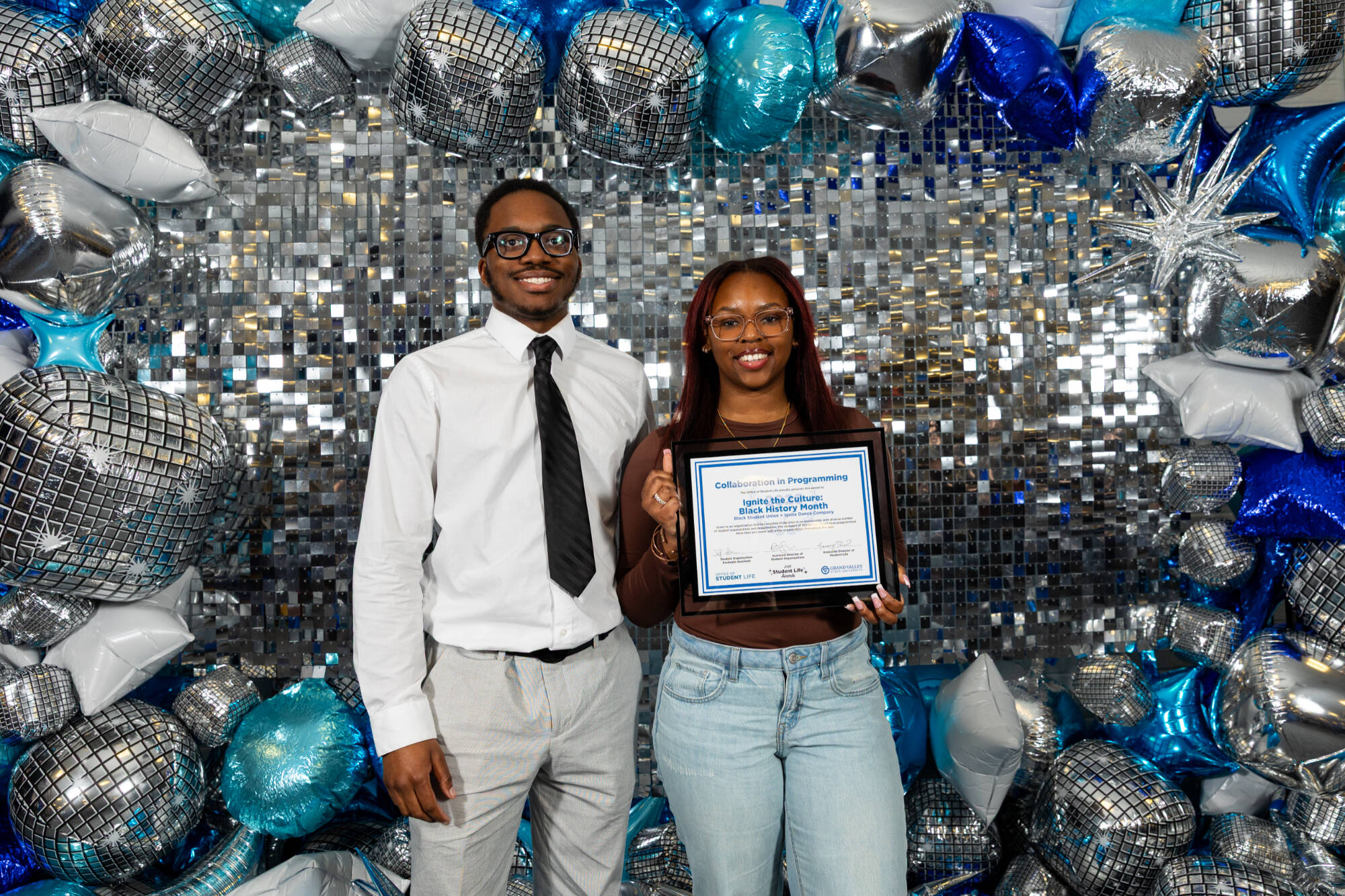Two individuals holding an award certificate